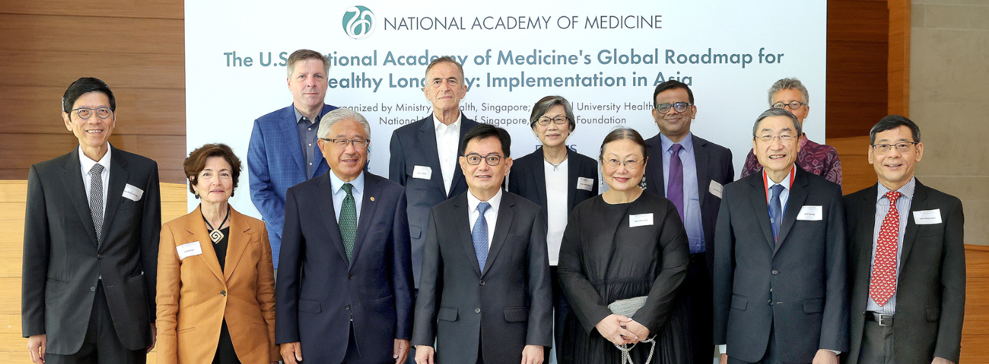 Group poses before "National Academy of Medicine's Global Roadmap for Healthy Longevity" sign.